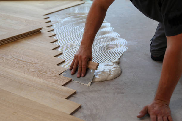Worker laying parquet flooring. Worker installing wooden laminate flooring.